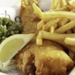 beer battered fish and chips in a basket with a slice of lemon