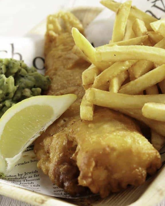 beer battered fish and chips in a basket with a slice of lemon