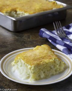 Cheesy homemade copycat Cracker Barrel hashbrown casserole on a plate and in a baking pan.