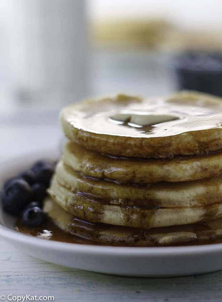 A stack of homemade Buttermilk Pancakes with syrup on a plate.