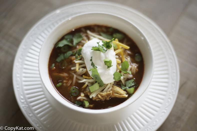 A bowl of chicken tortilla soup with sour cream and cheese on top. 