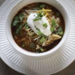 A bowl of tortilla soup with a dollop of sour cream on top