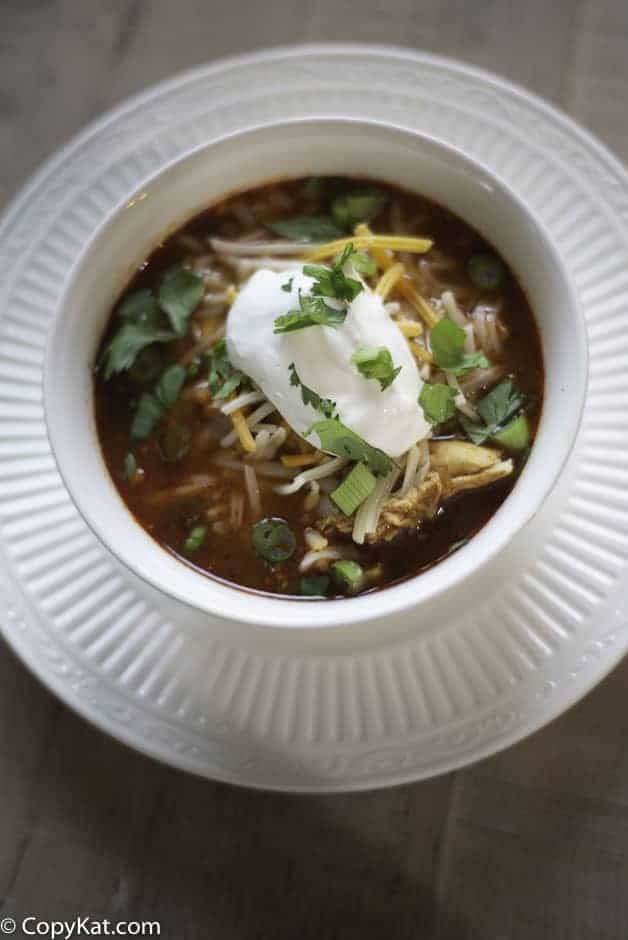 A bowl of tortilla soup with a dollop of sour cream on top 
