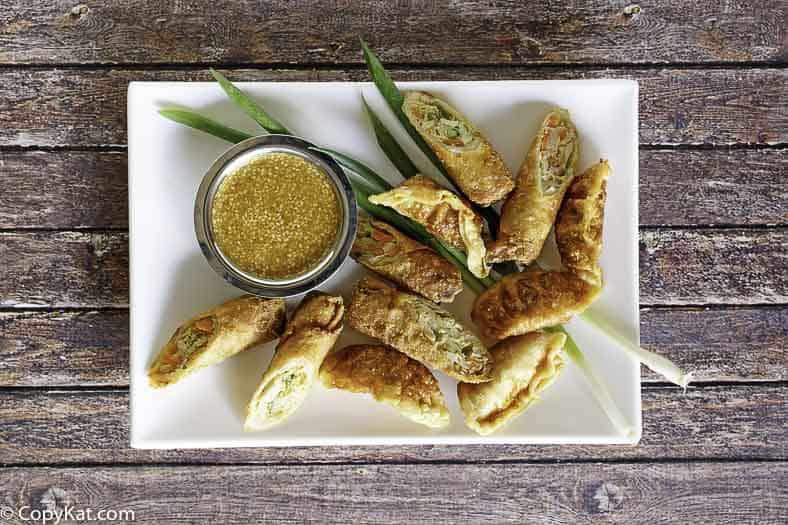 Mustard dipping sauce egg rolls on a platter