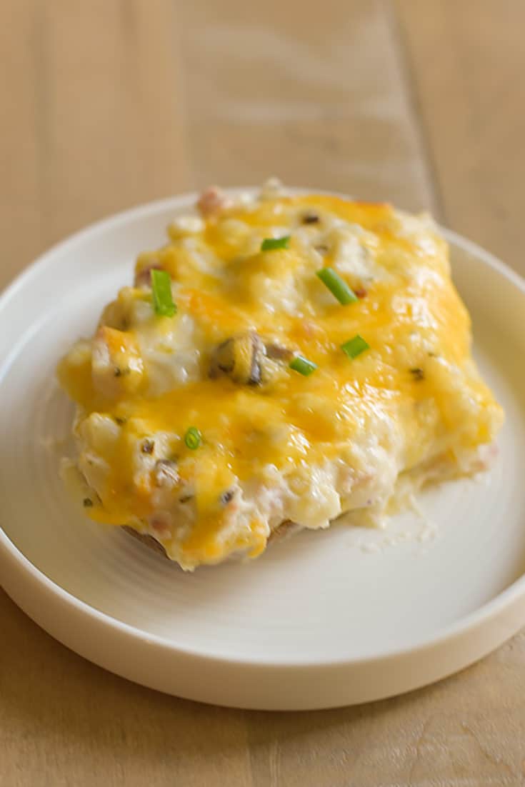 A twice baked potato with mushrooms, sour cream, and cheese 