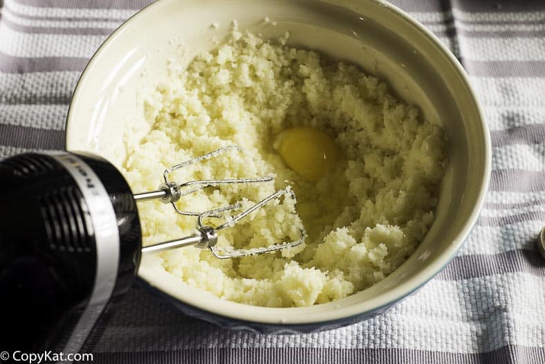adding an egg to butter and sugar that have been creamed together