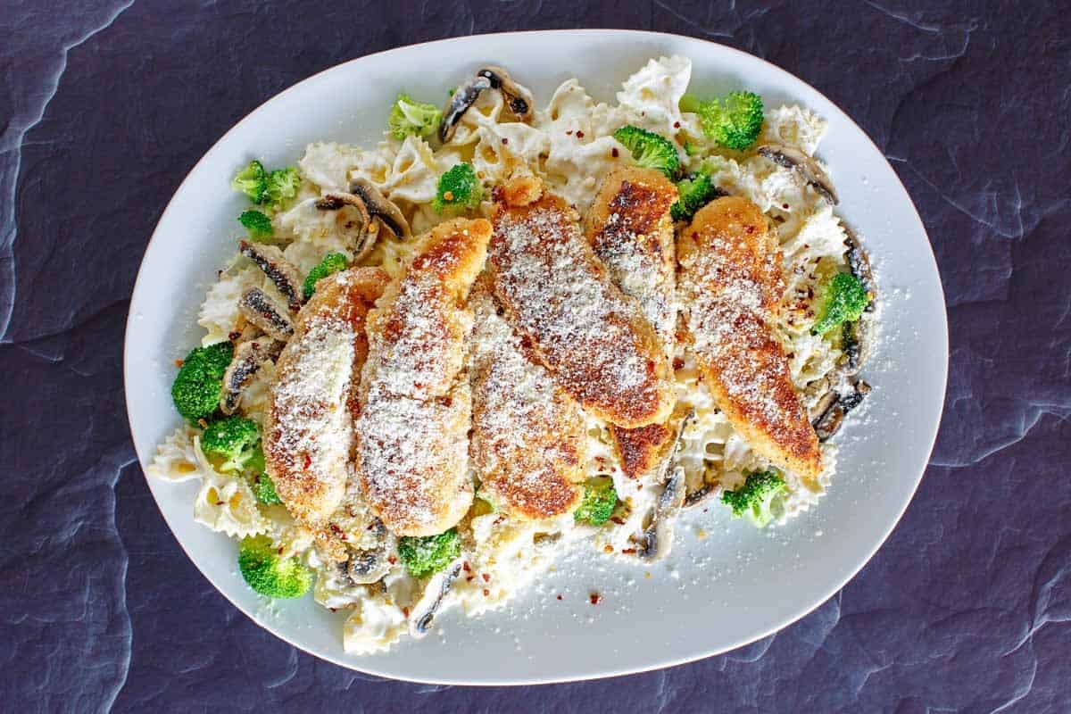 Pan-fried parmesan chicken with creamy sauce pasta.