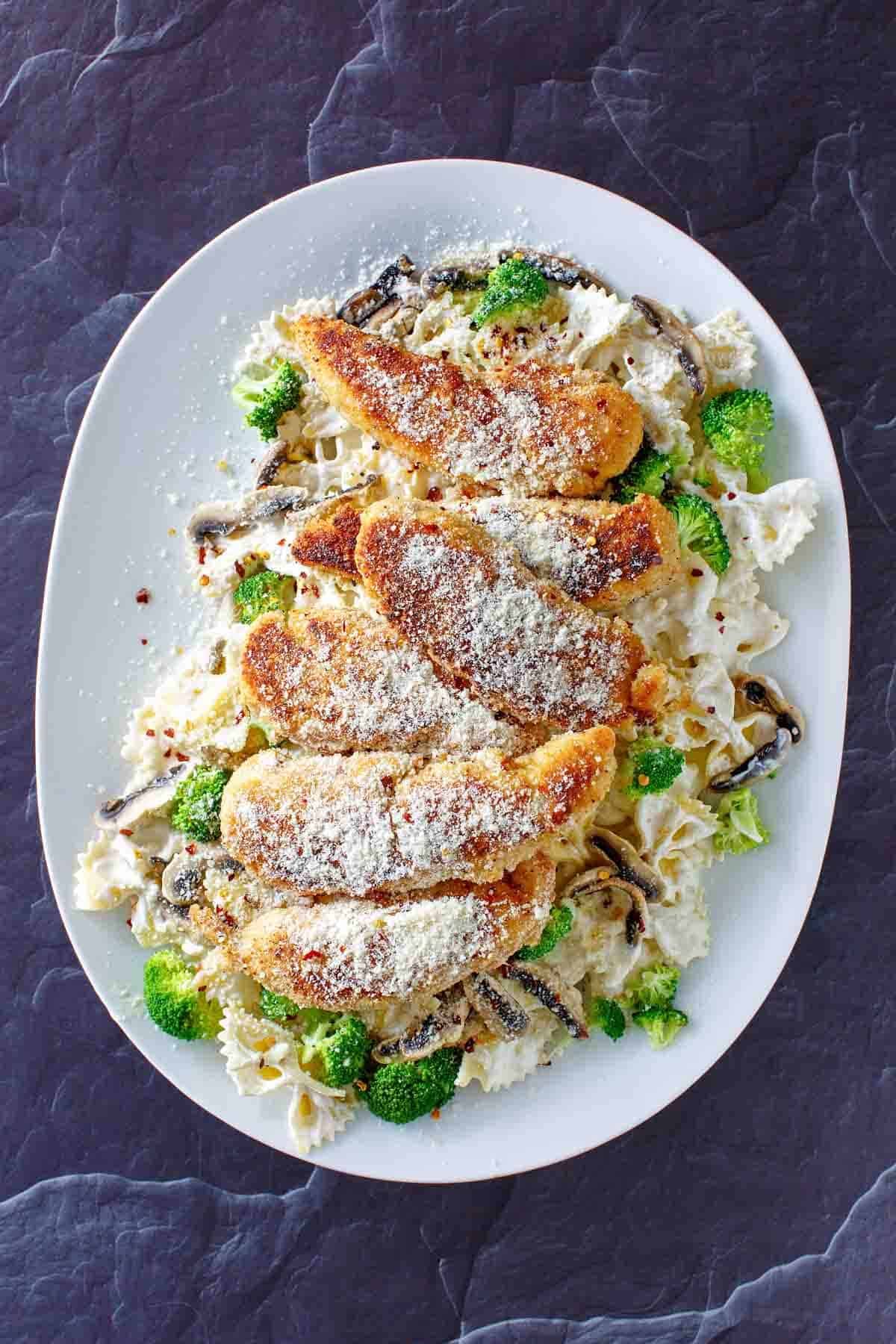 Parmesan chicken pasta with creamy sauce on a platter.