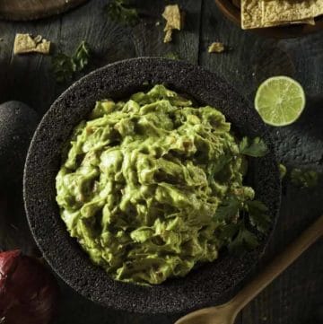 A bowl of guacamole made with fresh avocados and canned tomatoes.