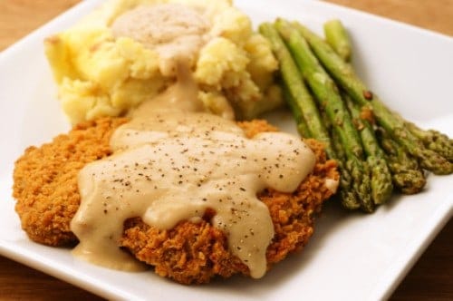 Beer battered chicken fried steak with gravy, mashed potatoes, and asparagus