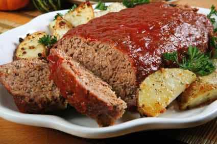 meatloaf with tomato sauce on a platter with roasted potatoes