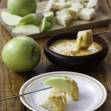 Homemade copycat Melting Pot Cheddar Cheese fondue with bread and apple slices.