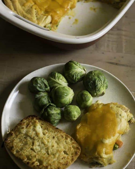 tuna stuffed crescent roll casserole on a plate with bread and Brussels sprouts