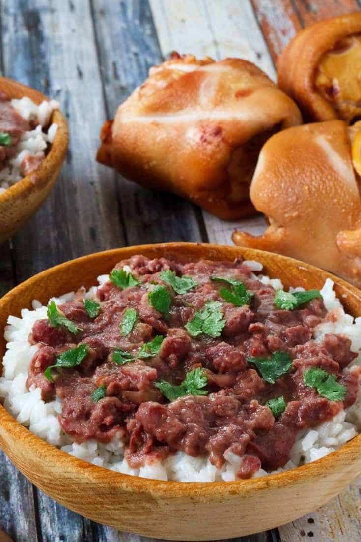 Homemade copycat Popeyes Red Beans and Rice in a bowl next to dinner rolls.