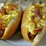 two hot dogs topped with truffle macaroni and cheese and bacon