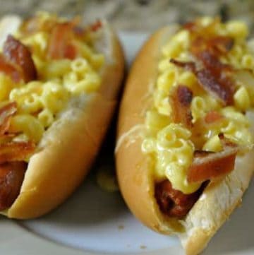 two hot dogs topped with truffle macaroni and cheese and bacon