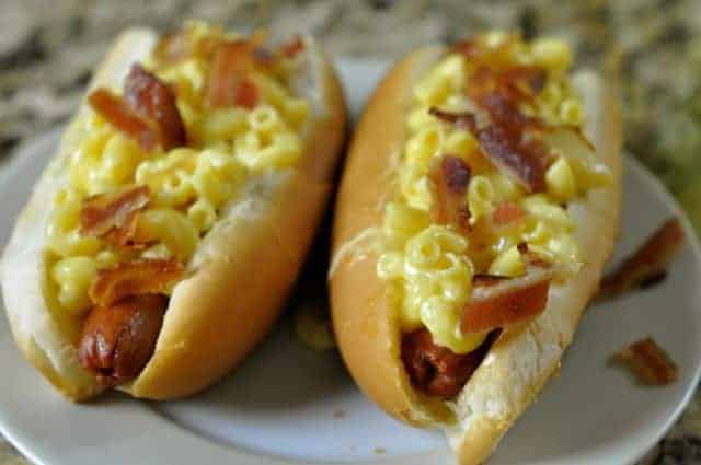 two hot dogs topped with truffle macaroni and cheese and bacon