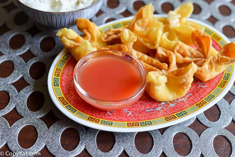 A plate of crab rangoons with Sweet and Sour Sauce dipping sauce