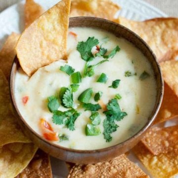 Applebees Queso Blanco dip in a bowl and tortilla chips on a platter.