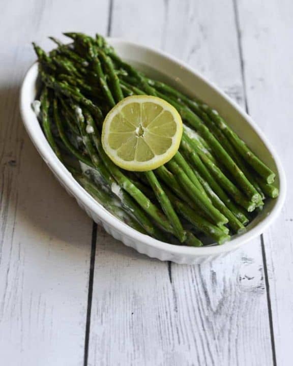 asparagus with cream sauce in a white serving dish