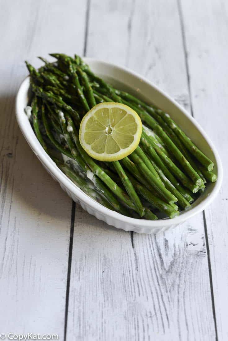 asparagus with lemon cream sauce in a white serving dish