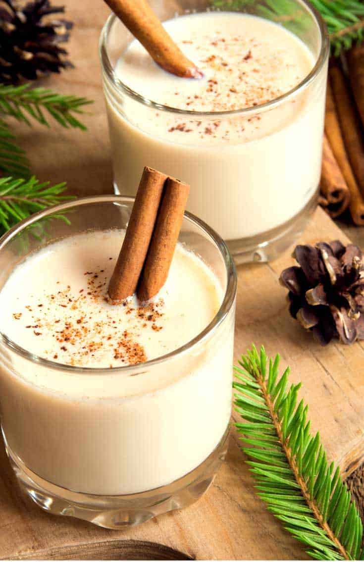 homemade spiked eggnog in glasses with cinnamon sticks as stirrers.