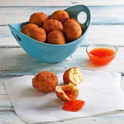 A bowl hush puppies with chili sauce