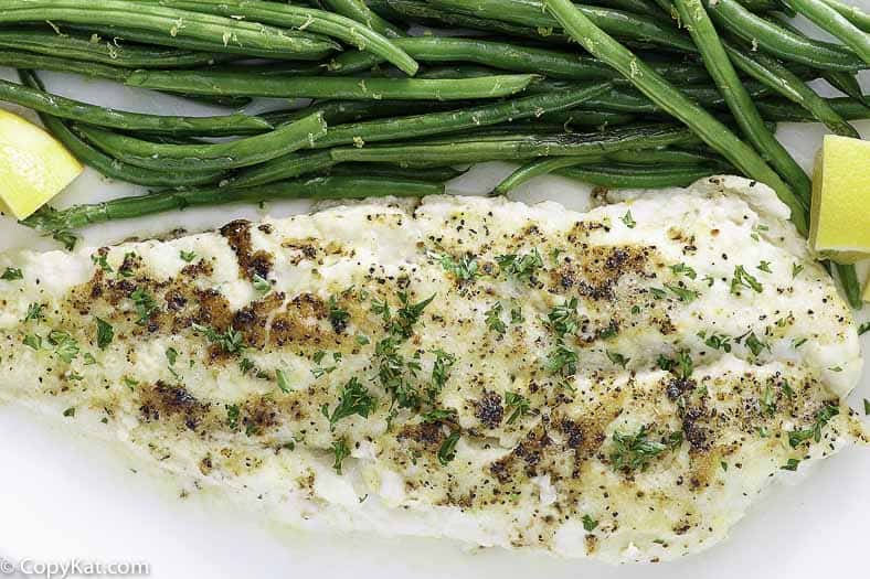 baked white fish on a plate with green beans