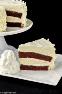 a slice of homemade Cheesecake Factory Red Velvet Cheesecake beside the cheesecake on a stand.
