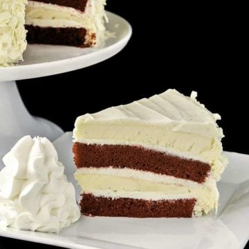 a slice of homemade Cheesecake Factory Red Velvet Cheesecake beside the cheesecake on a stand.