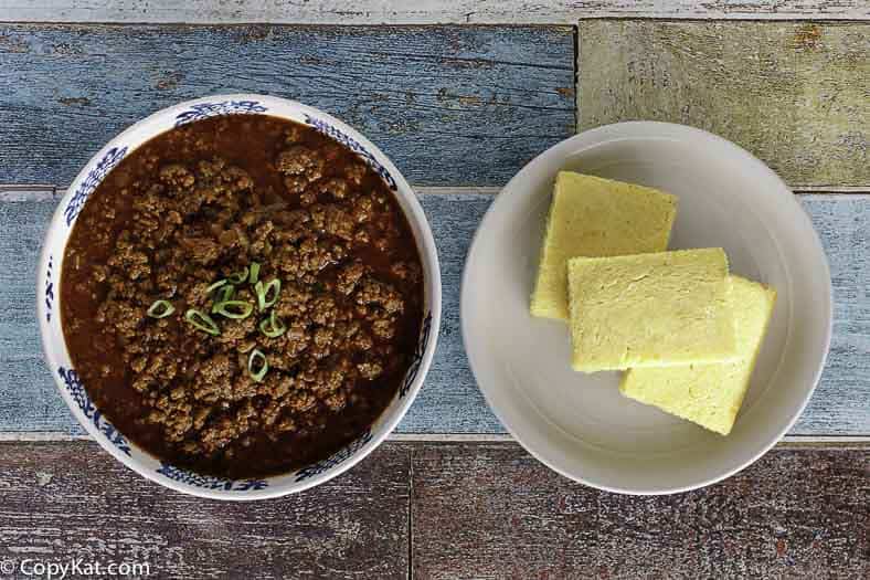 A bowl of homemade Chili's original chili next to a plate of cornbread slices.