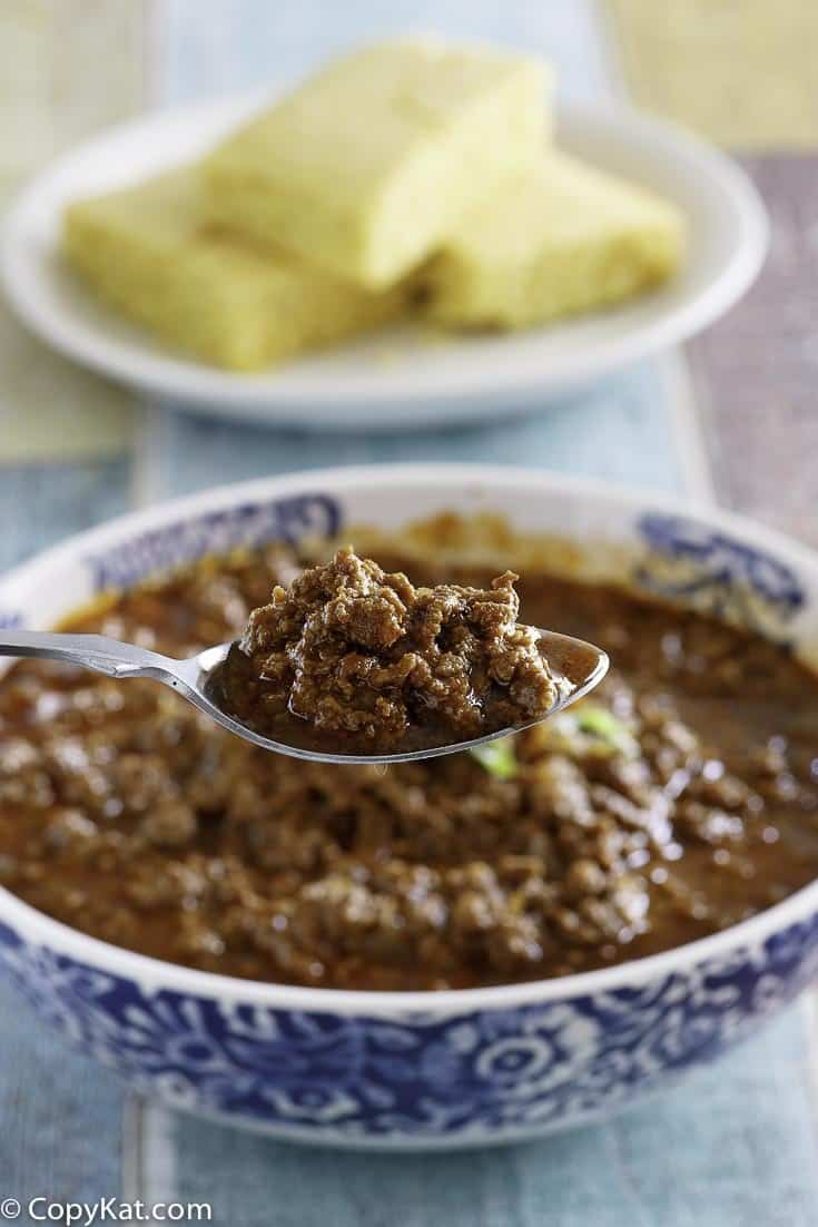 A spoon of homemade Chilis original chili over a bowl of it.