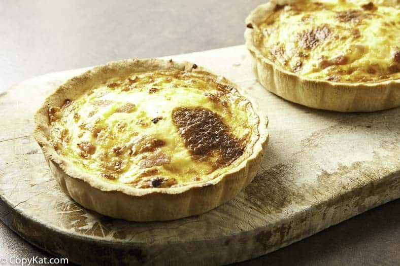 Two quiche lorraines on a bread board