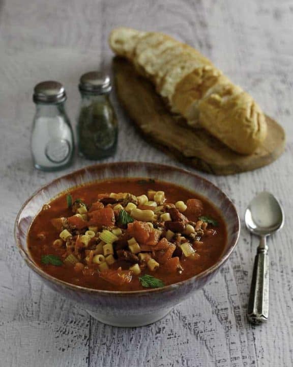 A bowl of homemade Olive Garden Pasta E Fagioli soup and a loaf of bread.