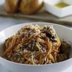 Instant Pot Italian Sausage Pasta in a bowl with rolls in the background.