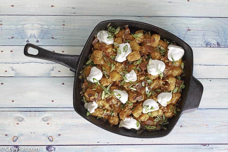 loaded tater tots in a cast iron skillet