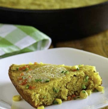 a plate with a slice of jalapeno cornbread with melted butter on top.