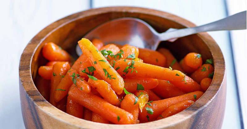Homemade copycat Cracker Barrel baby carrots and a spoon in a bowl.