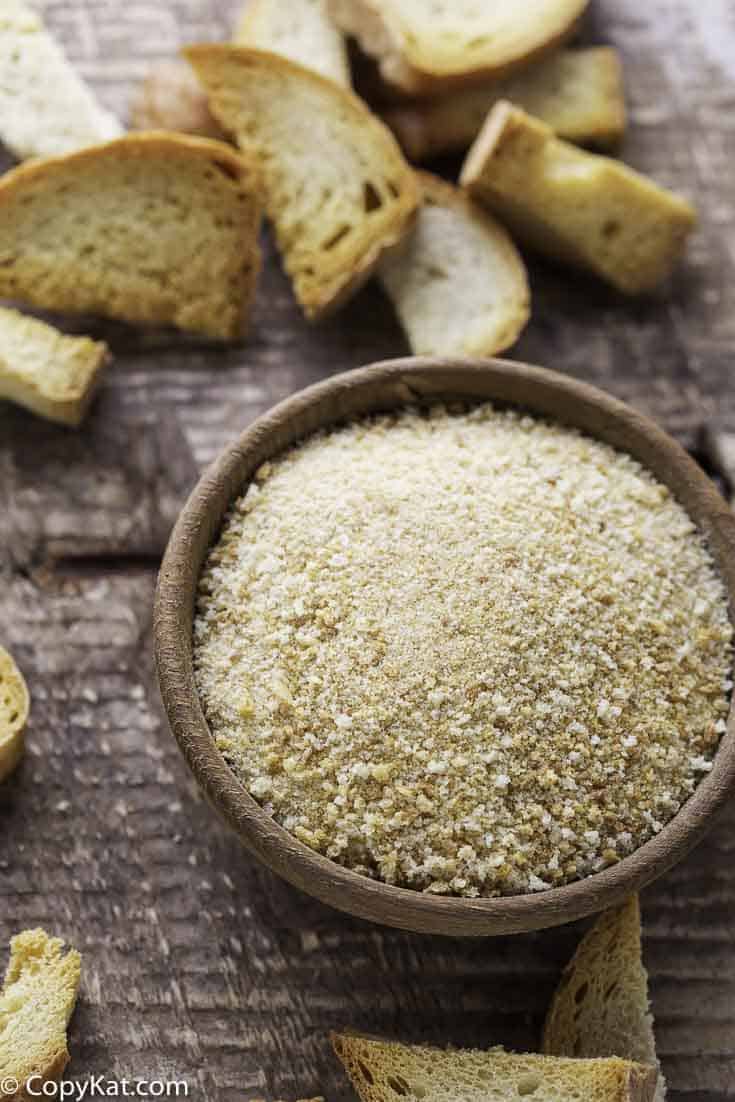 Homemade breadcrumbs in a bowl beside pieces of toasted bread.