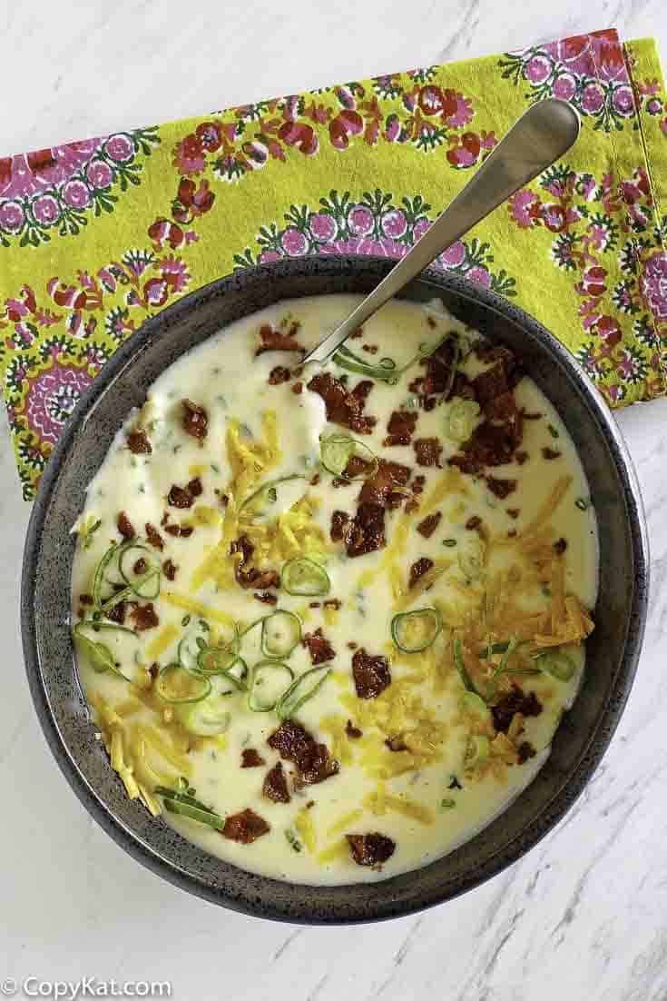 A bowl of baked potato soup topped with cheese, bacon, and green onions.