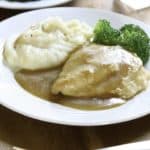 chicken covered in gravy, mashed potatoes, and broccoli on a plate