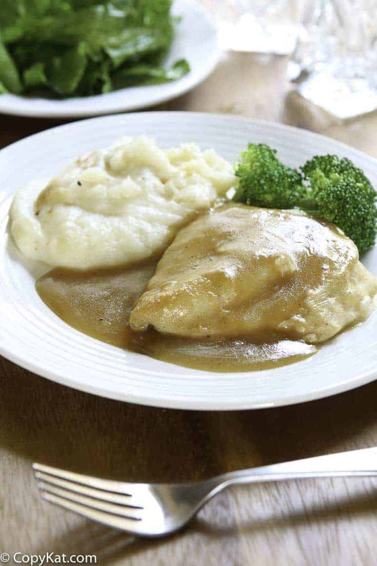 chicken covered in gravy, mashed potatoes, and broccoli on a plate