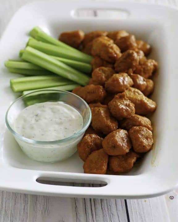Boneless Buffalo Chicken Bites on a platter with blue cheese dressing and celery sticks