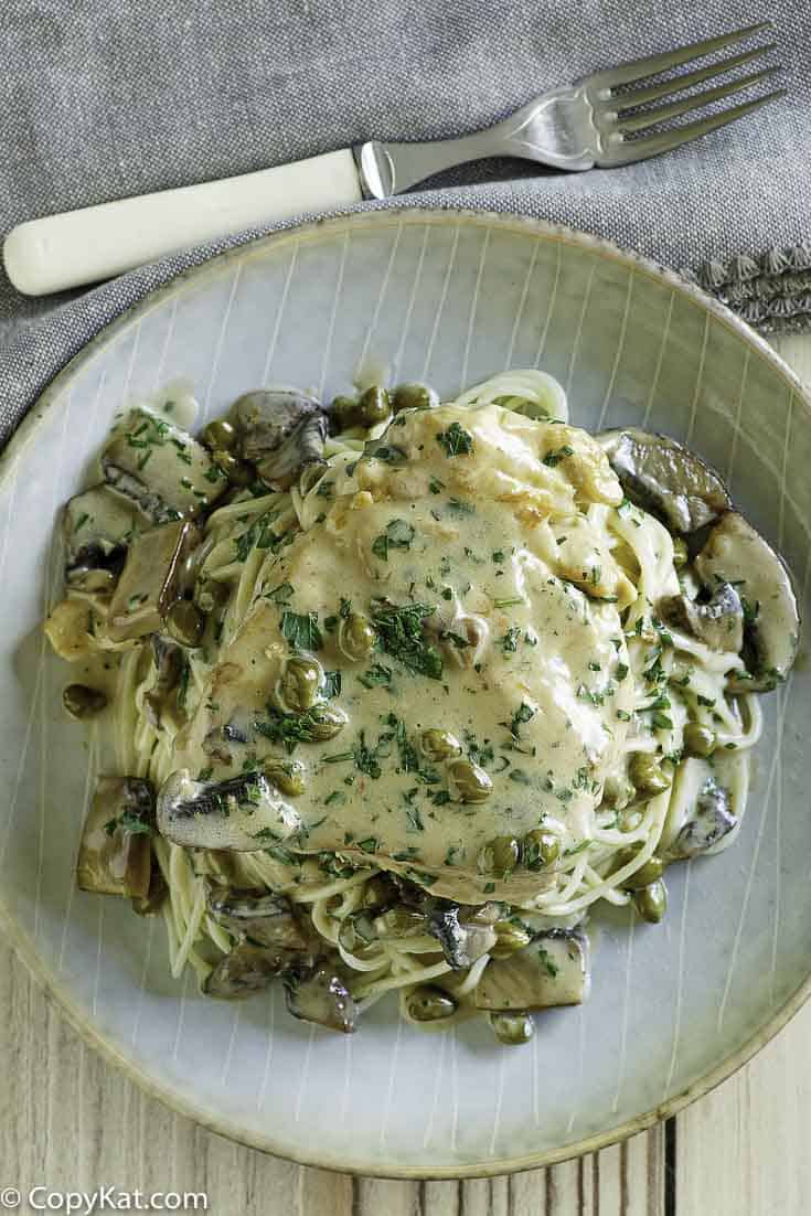 Homemade copycat Cheesecake Factory Chicken Piccata on a plate next to a fork.