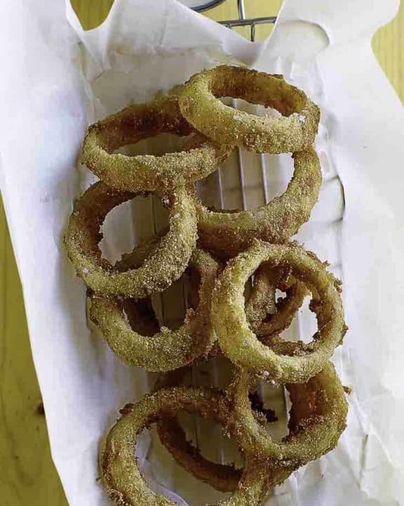 Homemade Sonic Onion Rings and dipping sauce on parchment paper in a metal serving basket.