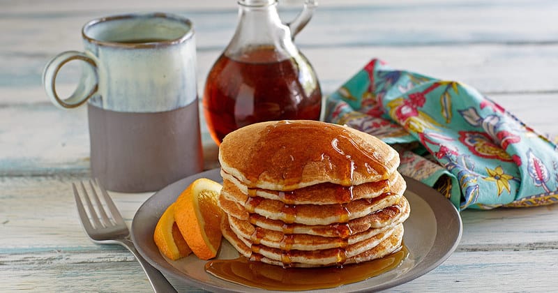 a stack of griddle cakes with syrup on a plate