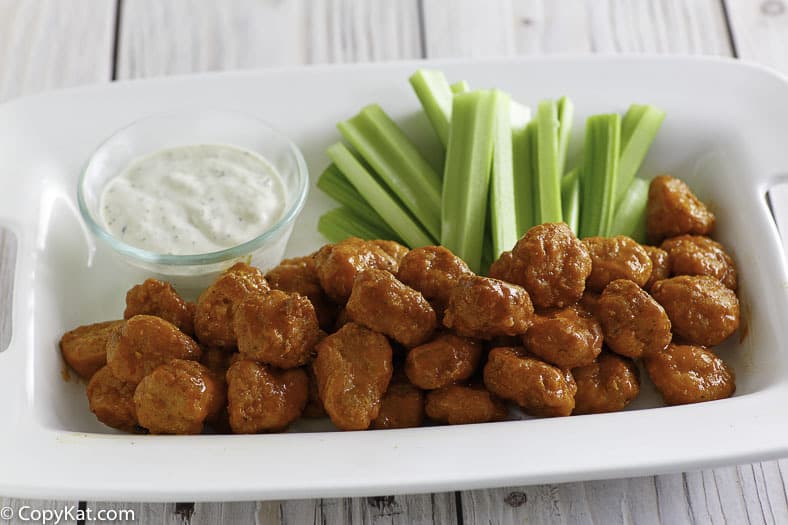 Boneless Buffalo Chicken Wings, blue cheese dressing, and celery sticks on a platter