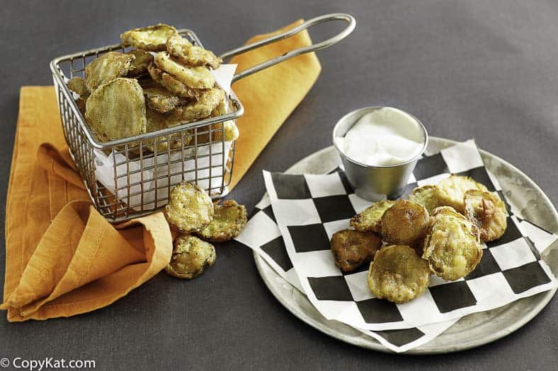 fried pickles in a fryer basket and on a plate