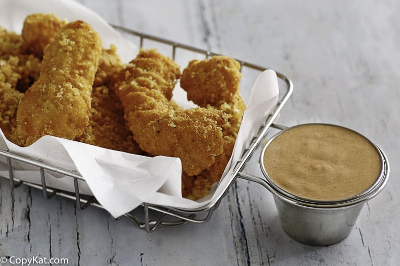 Homemade Red Robin Campfire Sauce in a ramekin next to a basket of chicken fingers.