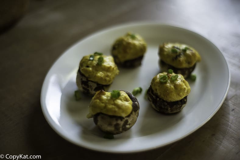 five ham and cream cheese stuffed mushrooms on a plate.